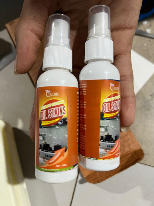 Two bottles of kitchen oil stain remover with orange labels held in hand for cleaning kitchen oil stains